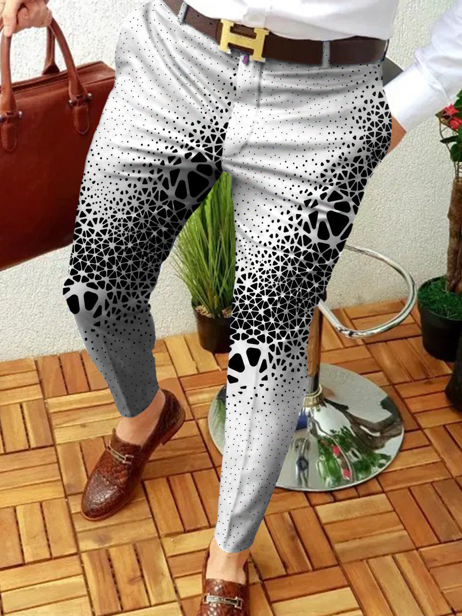 Person wearing a patterned gray and black pant with brown shoes on a wooden floor.