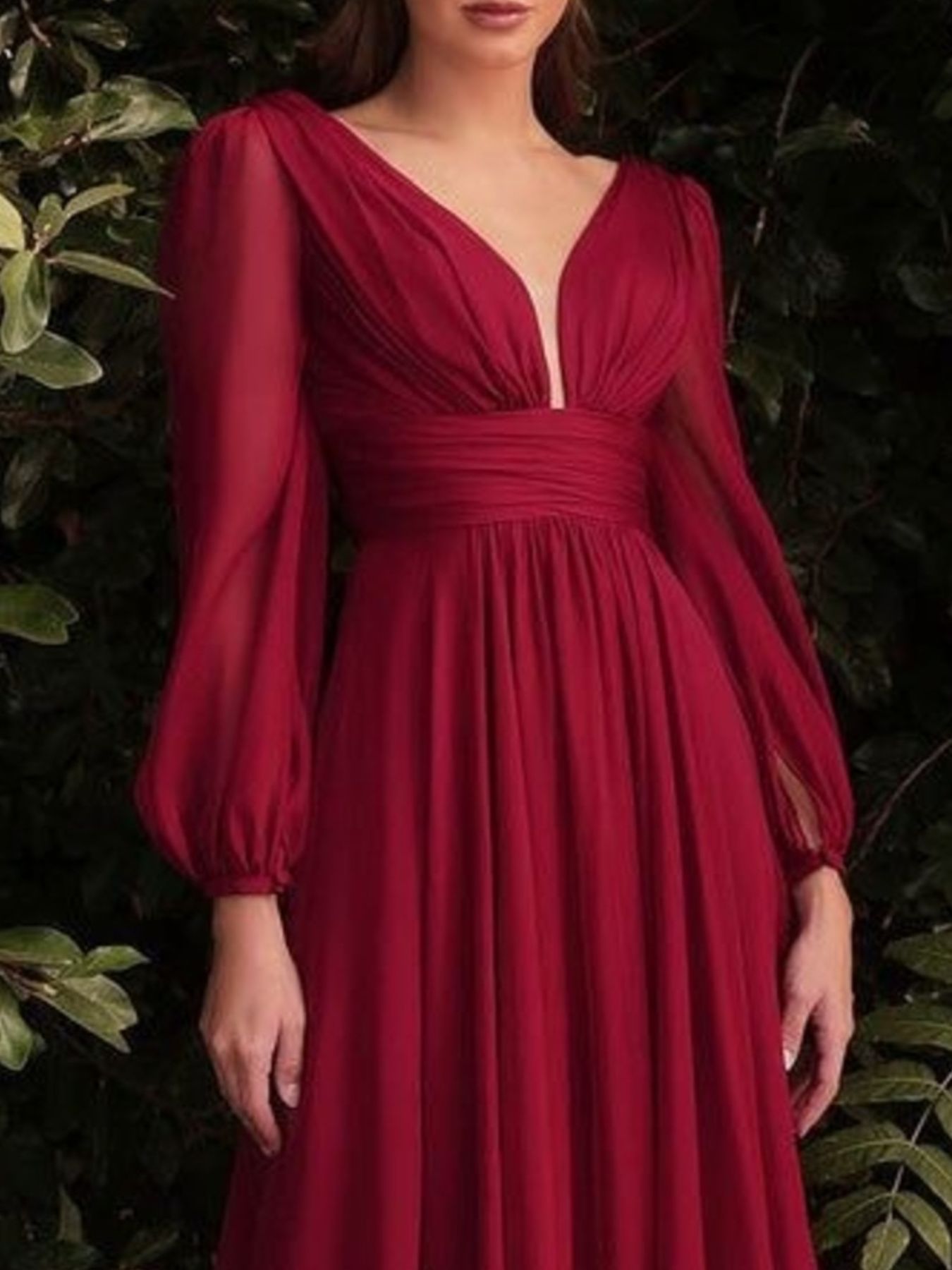 Red dress with long sleeves worn by a person against a dark background