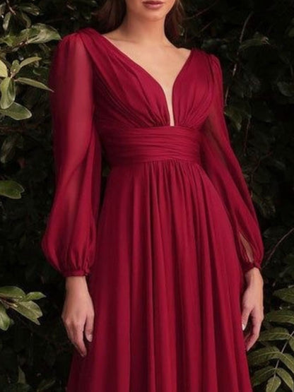 Red dress with long sleeves worn by a person against a dark background