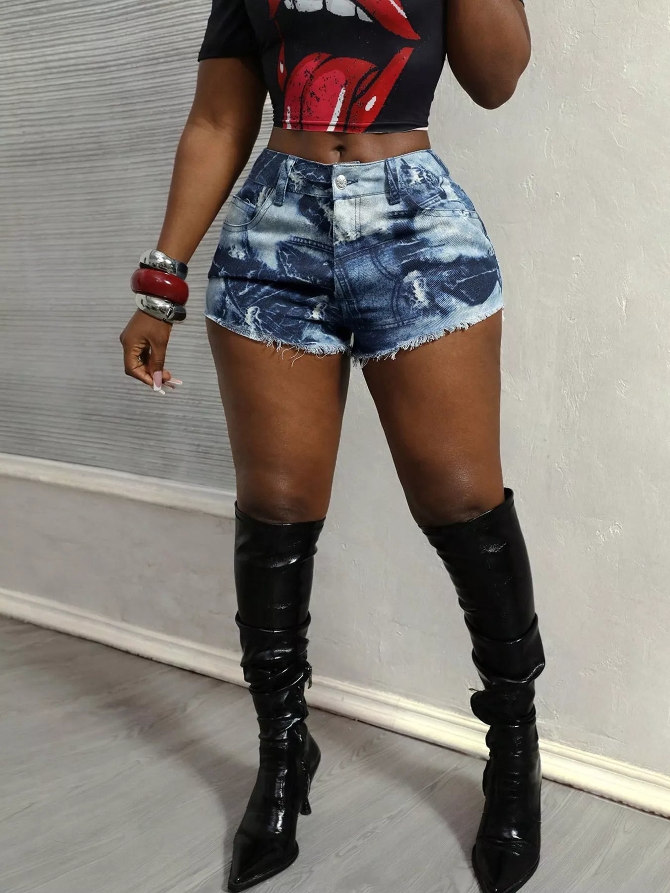 Person wearing denim shorts and black knee-high boots against a neutral background