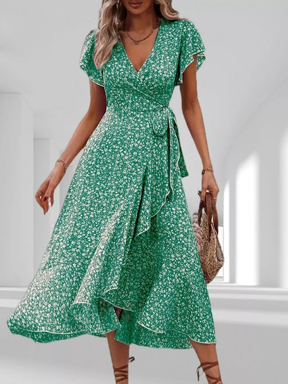 Woman wearing a green floral dress in a bright room.