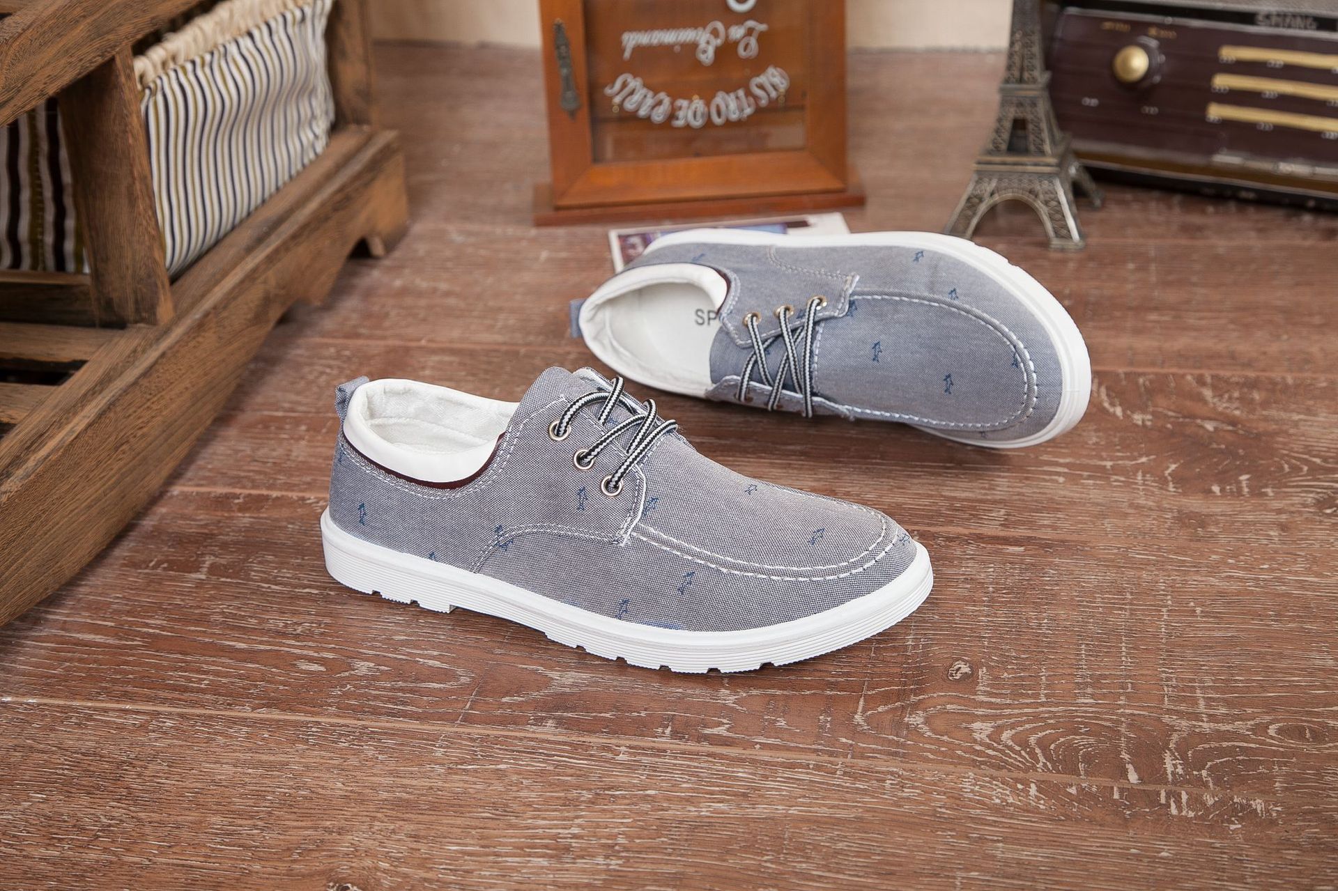 Pair of gray shoes with white soles on a wooden floor.