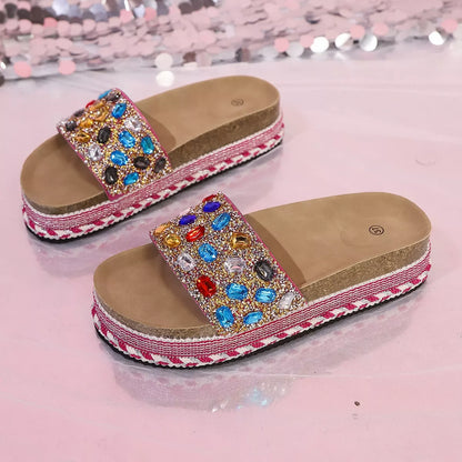 Decorative sandals with gemstones worn by a person on a glittery background