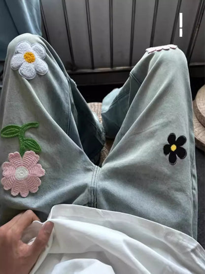 Light blue denim jacket with floral patches on a neutral background