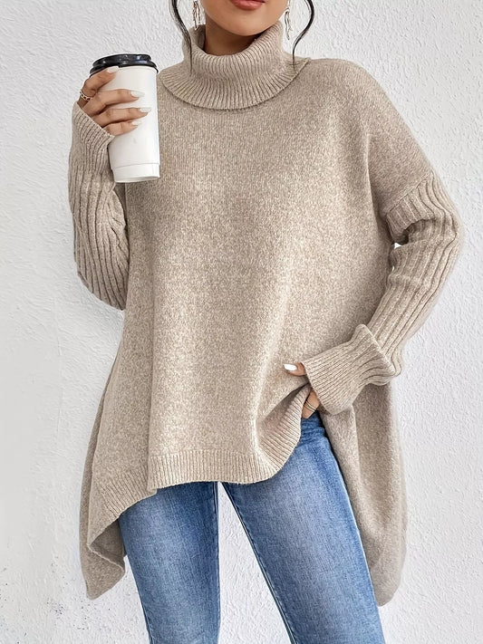 Person wearing a beige turtleneck sweater and blue jeans, holding a white cup with a black lid.