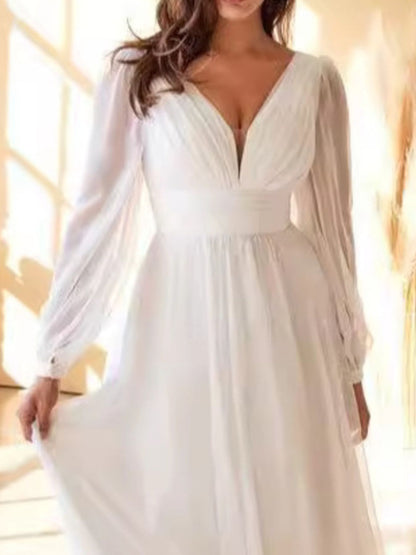 White dress with long sleeves and a deep neckline on a blurred background