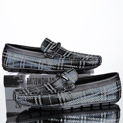 Black and silver patterned loafers on a reflective surface with a white background