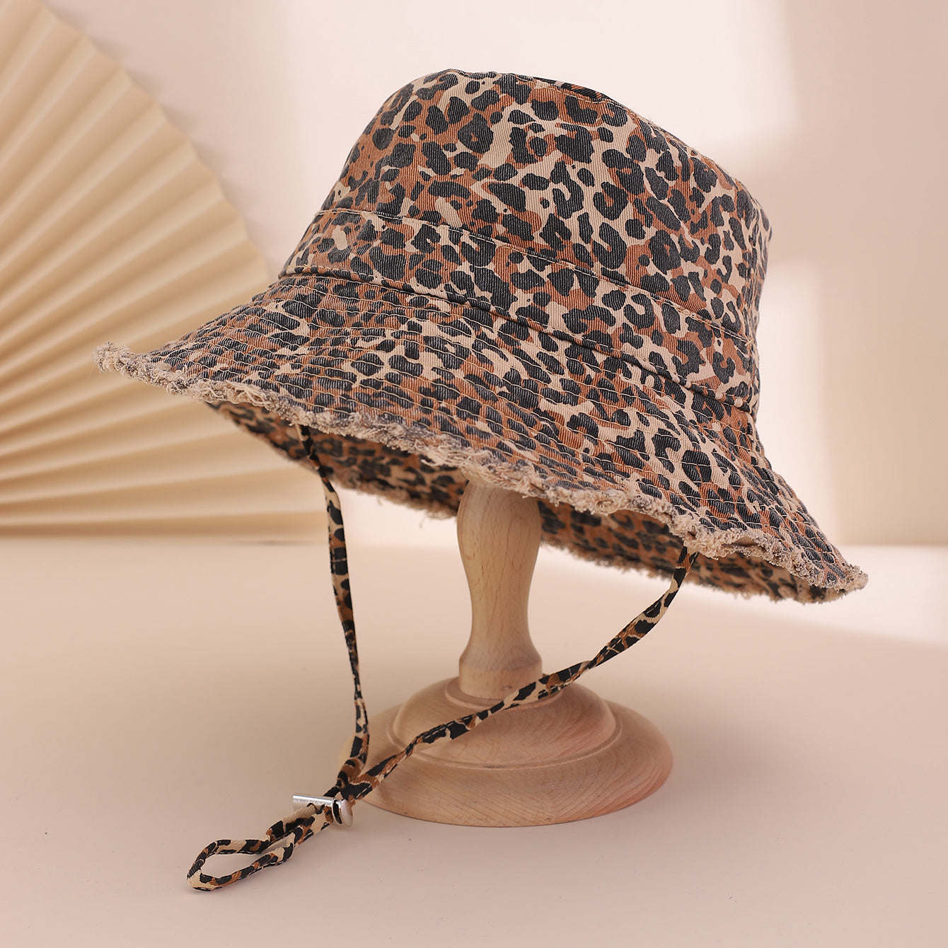 Leopard print bucket hat with a strap on a beige background