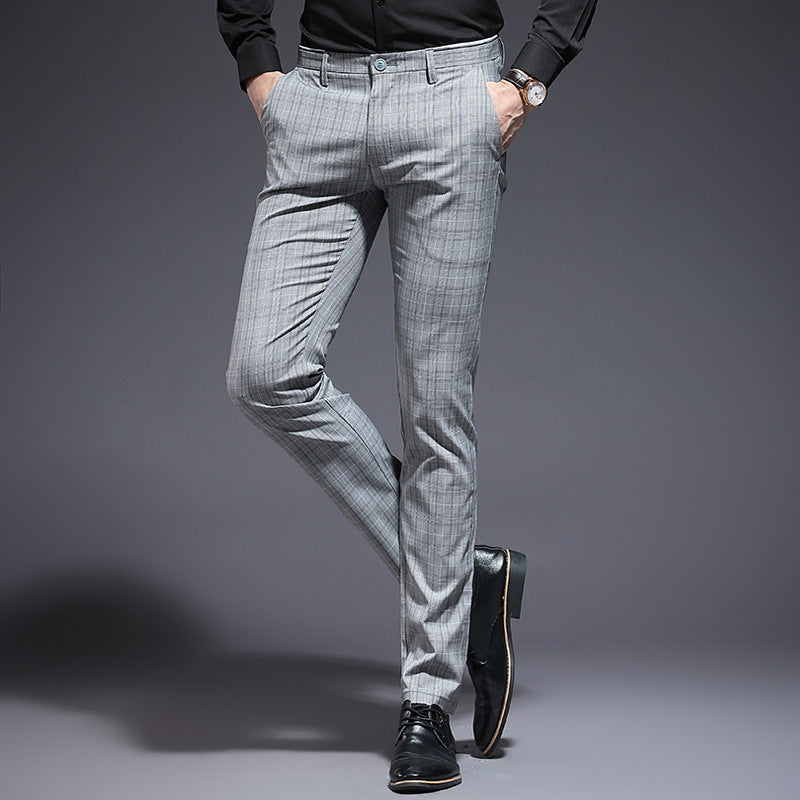 Person wearing gray checkered pants and black shoes on a gray background