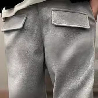 Close-up of gray pants with two front pockets on a neutral background
