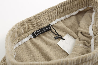 Close-up of a beige textured fabric with a brand tag on a white background