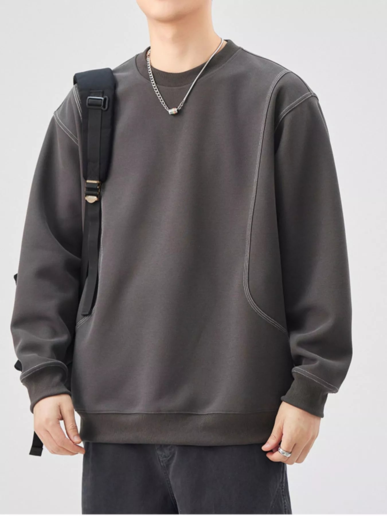 Person wearing a dark gray sweatshirt with a plain background