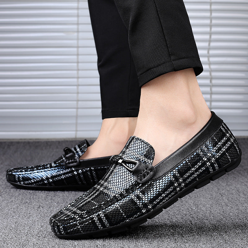 Black and silver loafers worn with black pants on a neutral background