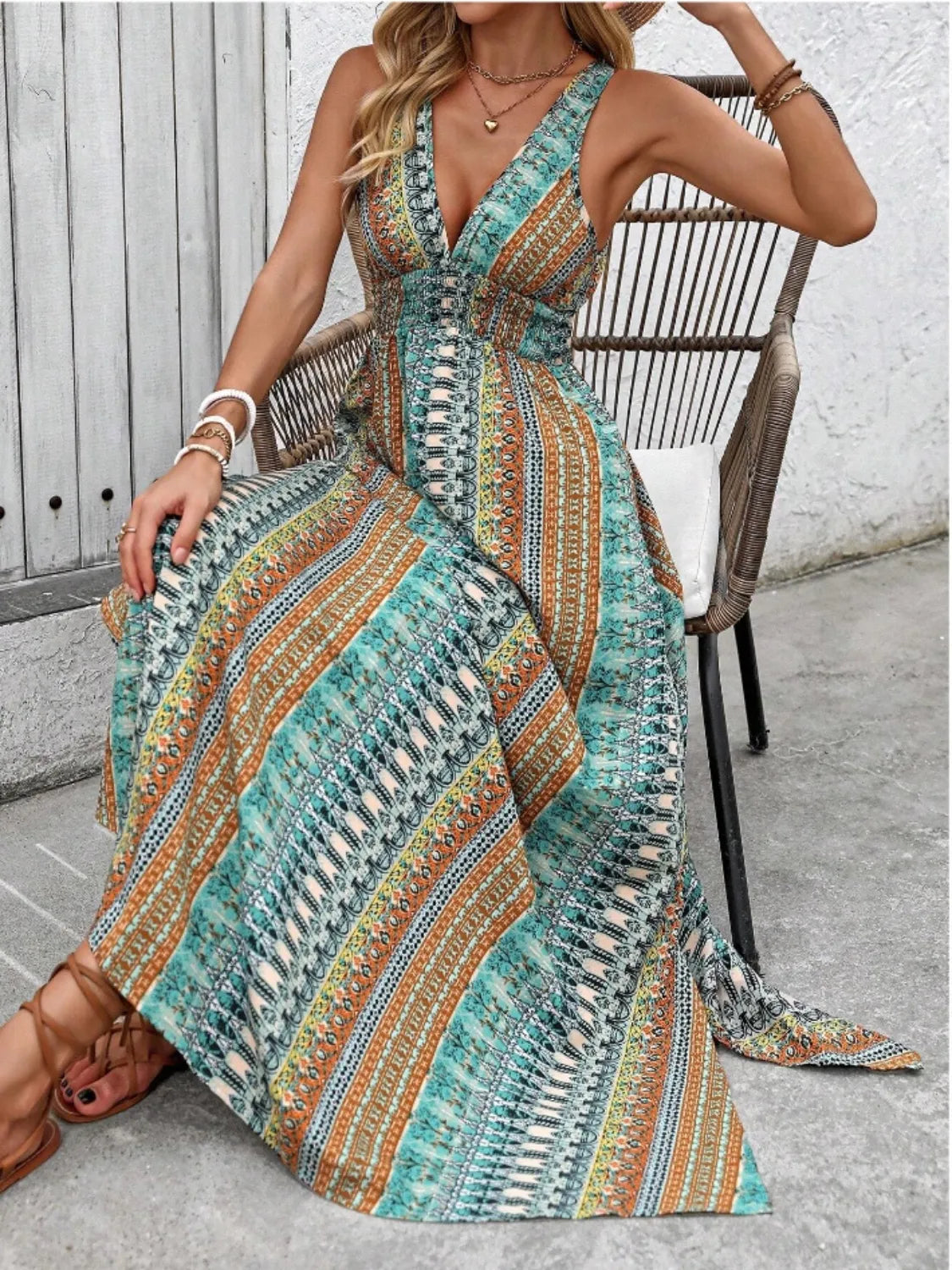 Woman wearing a patterned dress sitting on a chair outdoors.