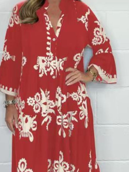 Red dress with white floral patterns worn by a person against a white wall.