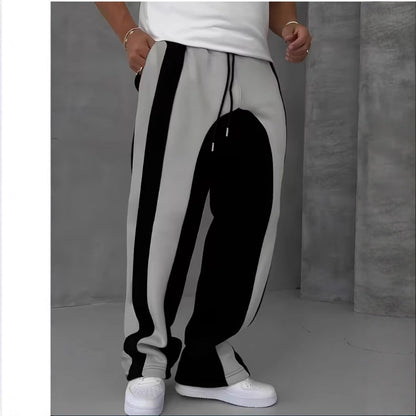 Person wearing gray sweatpants with black and white stripes against a plain background