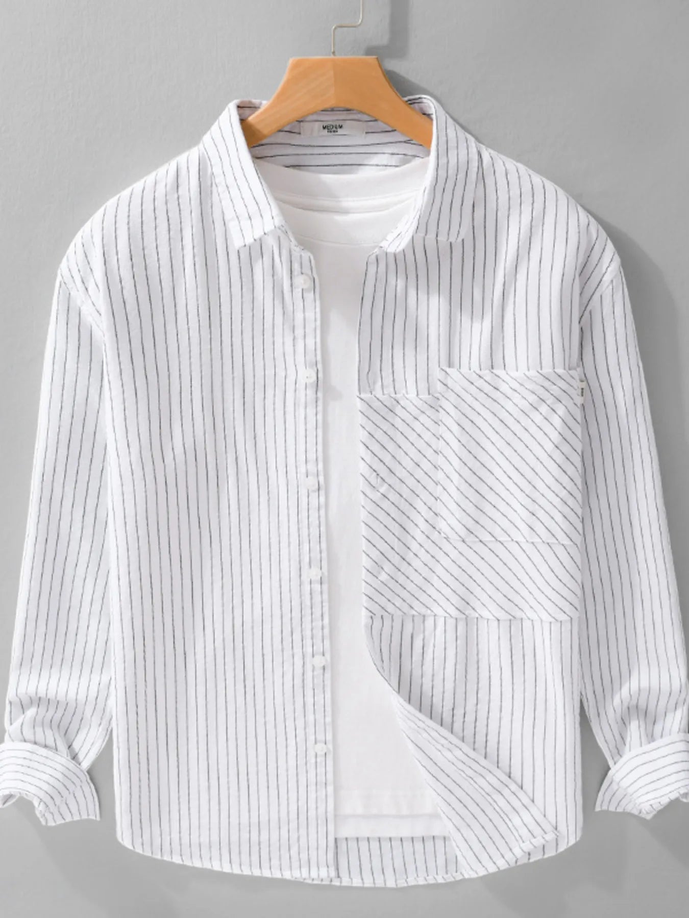 White and gray striped shirt on a hanger against a gray background
