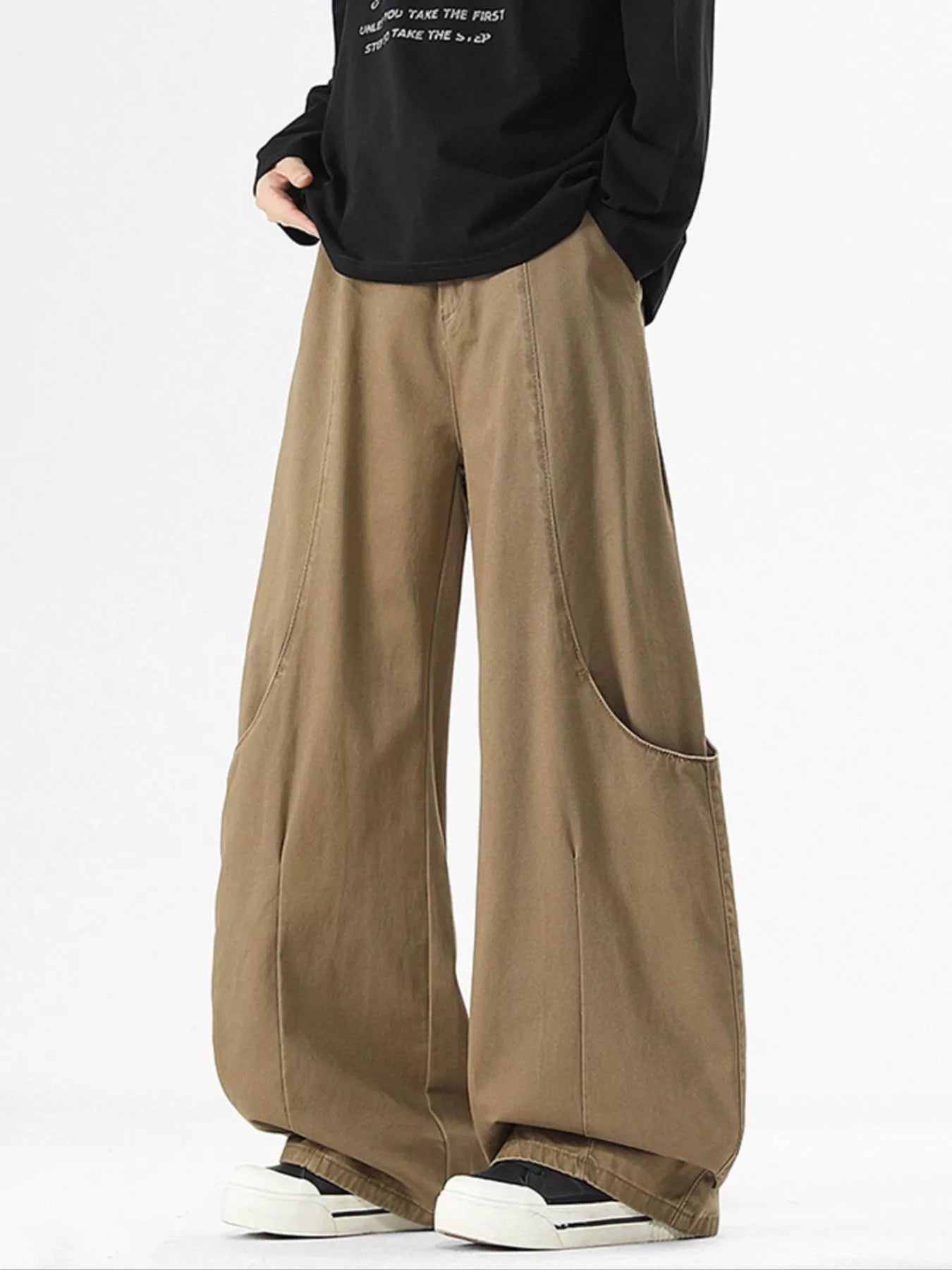 Person wearing brown wide-leg pants with a black top on a white background