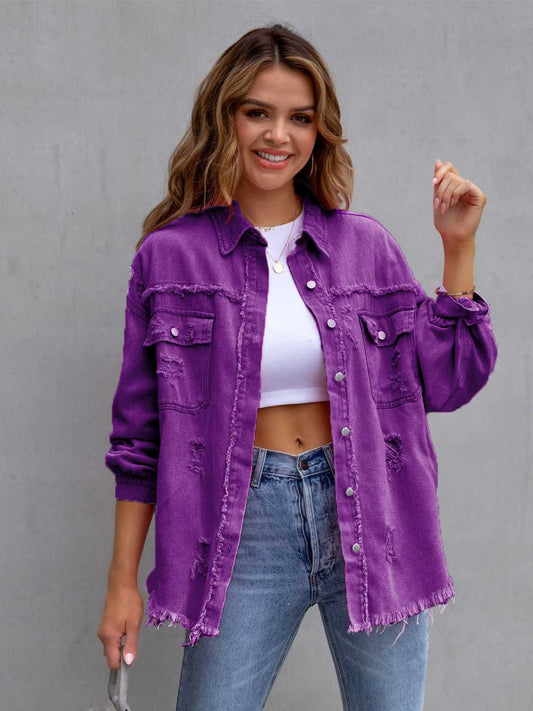 Woman wearing a purple denim jacket over a white top and blue jeans against a gray background