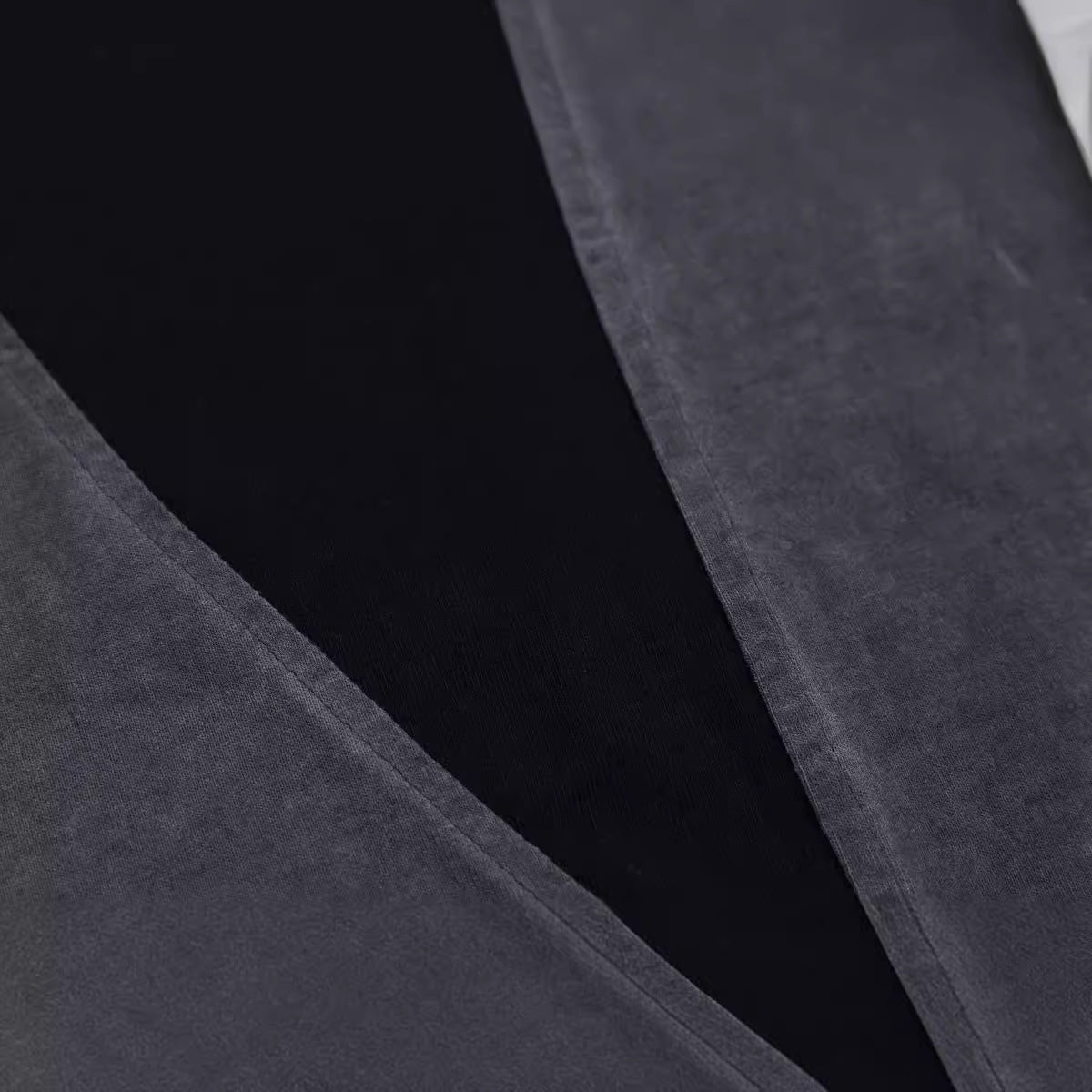 Close-up of dark gray fabric with a subtle pattern on a black background