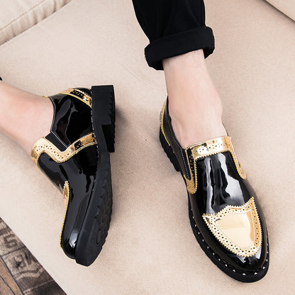 Black shoes with gold accents worn by a person on a beige surface