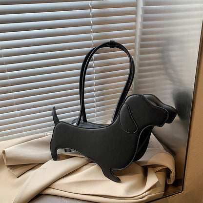Black dog-shaped handbag on beige fabric with window blinds in the background