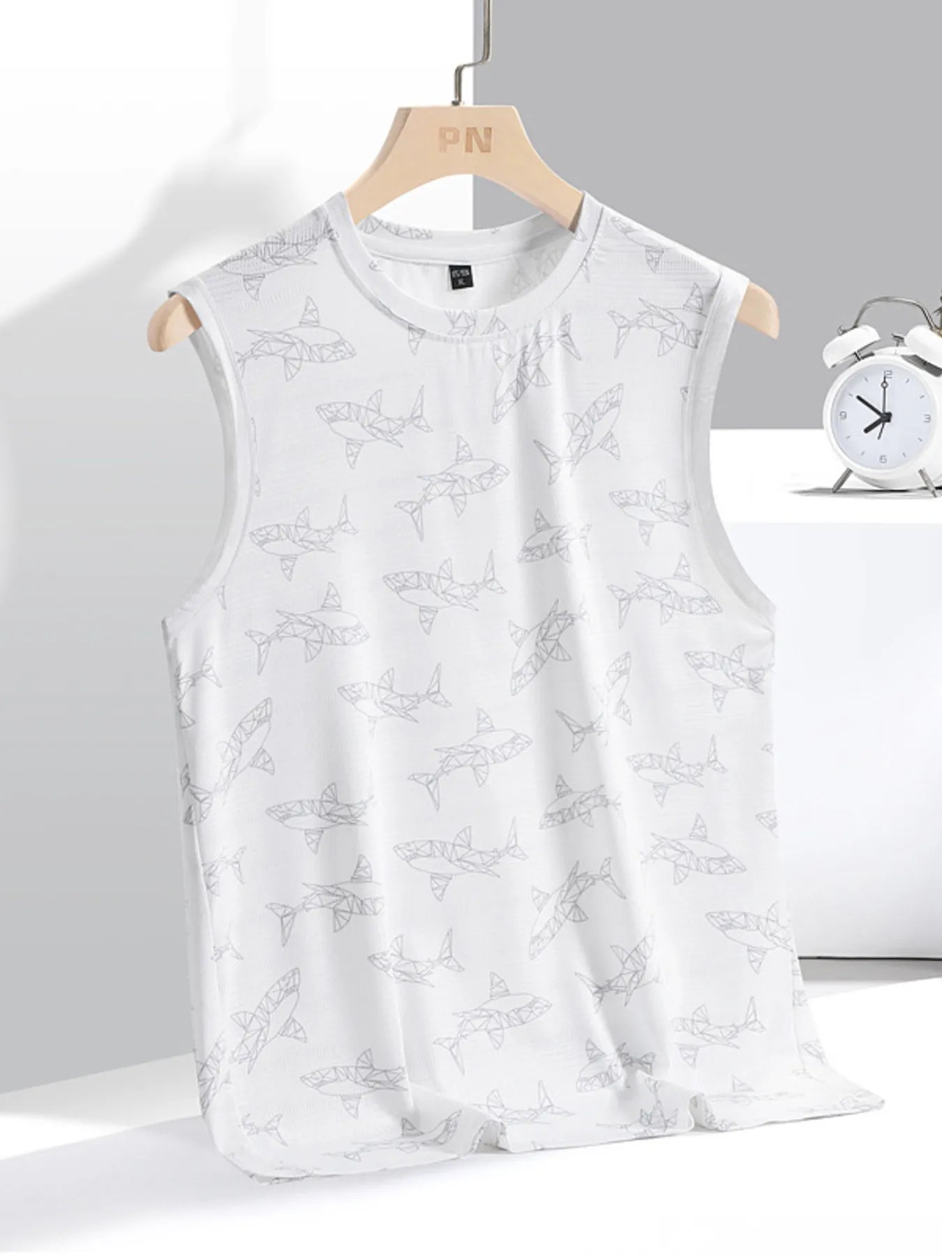 White sleeveless top with black text pattern on a hanger against a gray background.