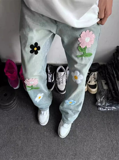Light blue jeans with floral patches worn by a person, standing on a carpeted floor.