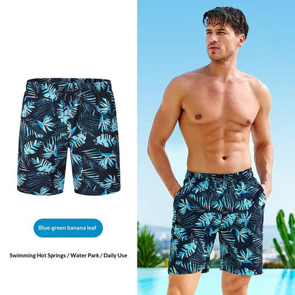 Man wearing blue-green banana leaf patterned swim shorts with a clear sky background