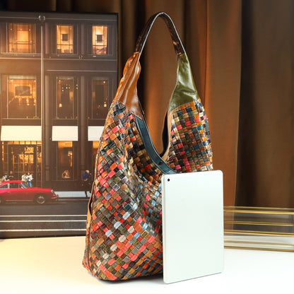Multicolored woven handbag with a white phone on a reflective surface, cityscape background
