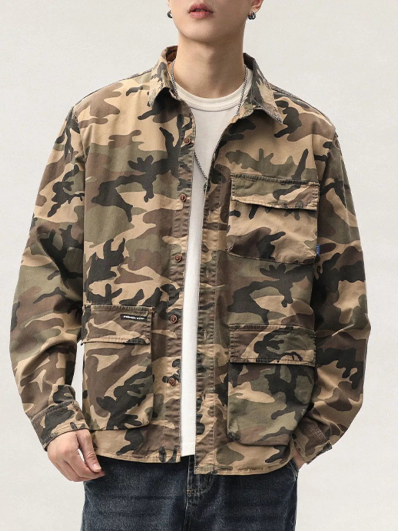Person wearing a camouflage jacket on a plain background