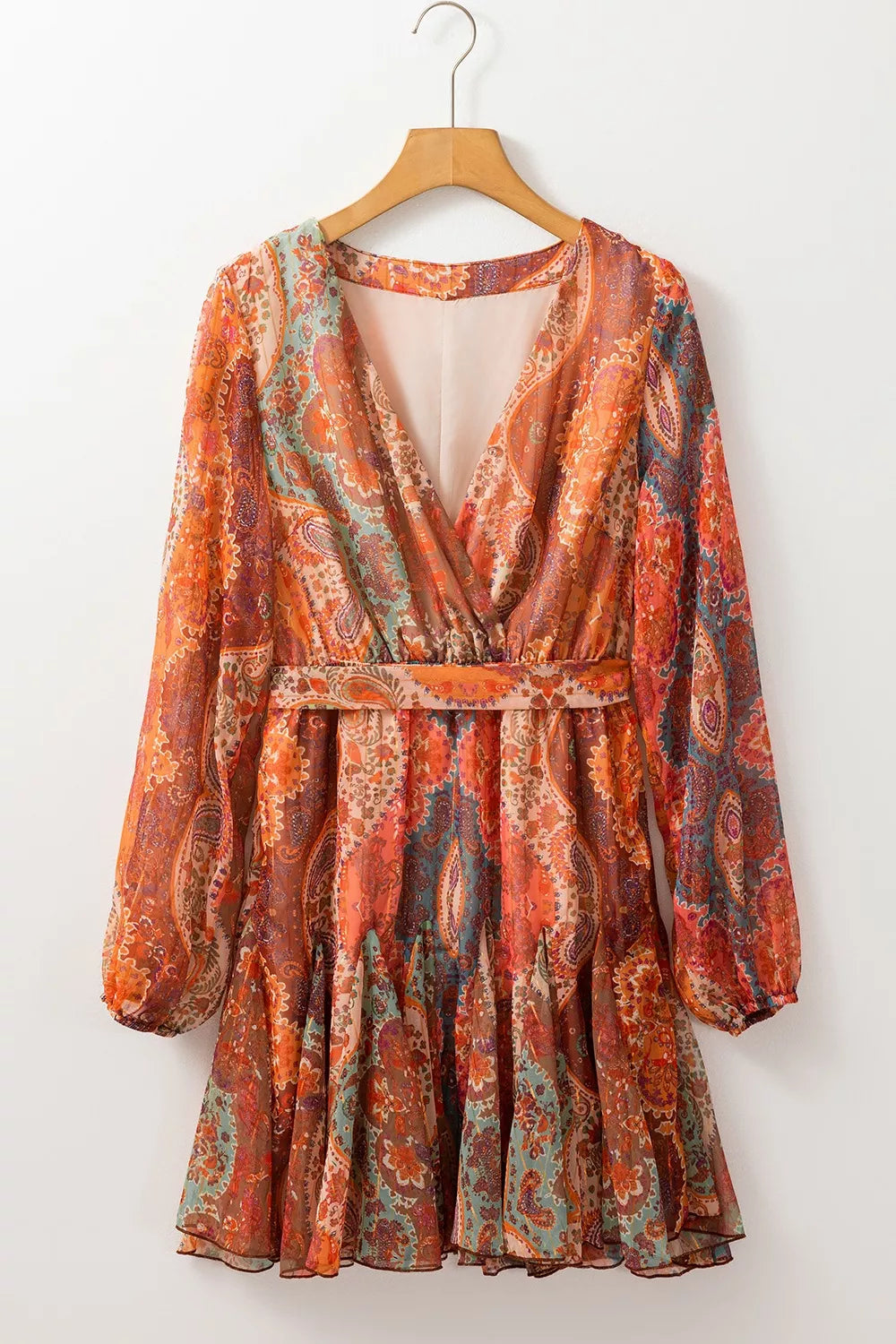 Patterned dress on a wooden hanger against a white background