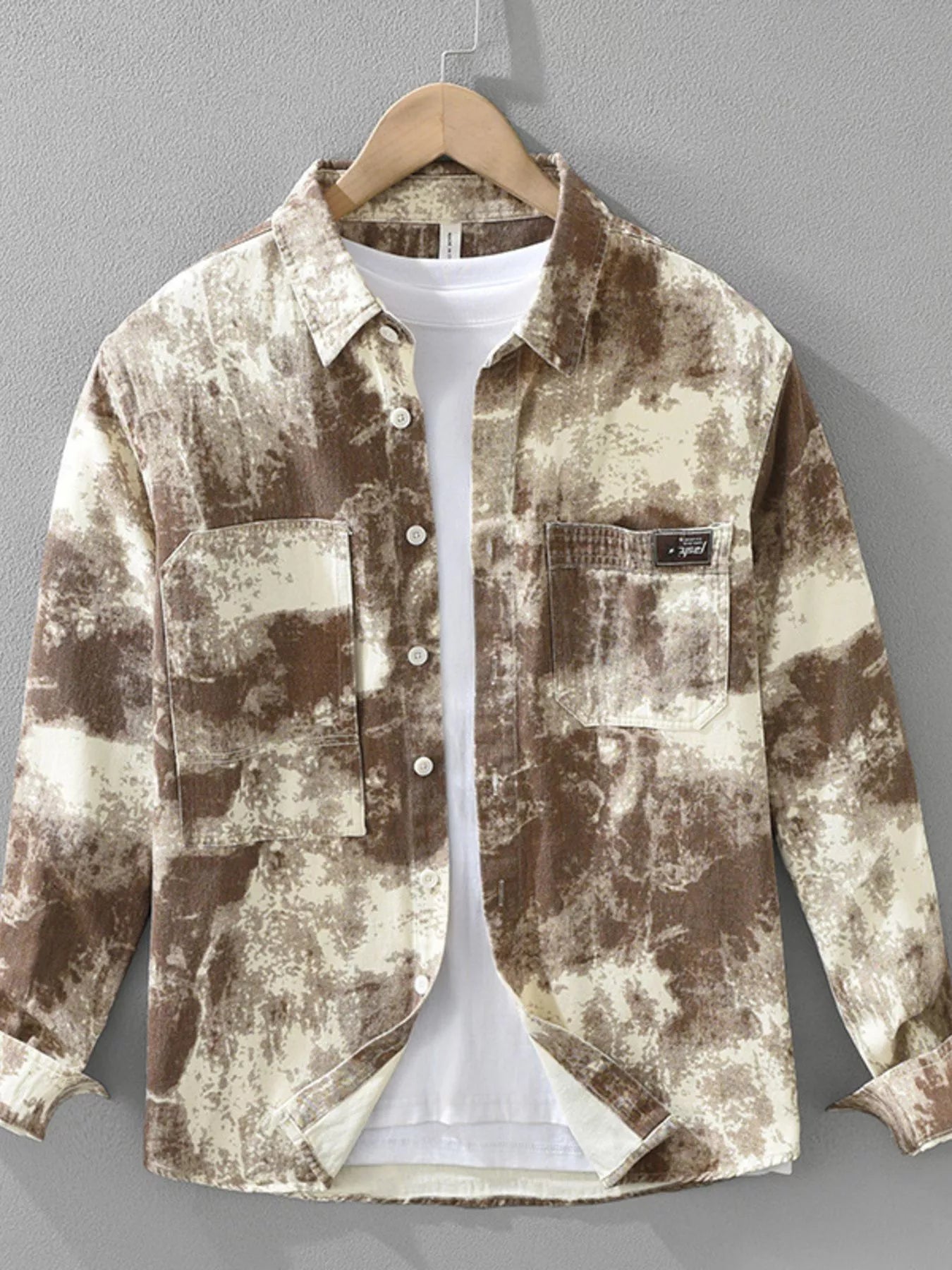 Abstract patterned shirt on a hanger against a gray background