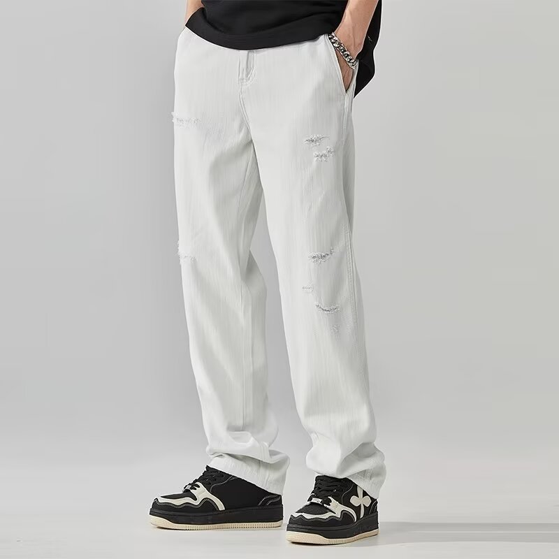 Person wearing light gray pants with patches on a plain background