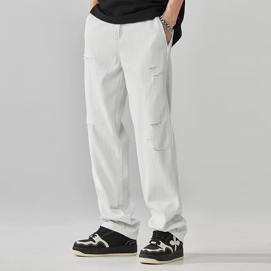 Person wearing light gray pants with patches on a plain background