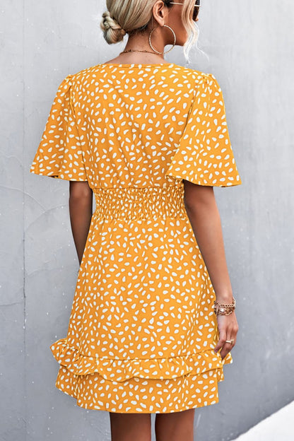 Woman wearing a yellow dress with white pattern against a gray background