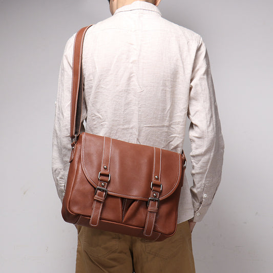Person wearing a brown leather satchel bag on a plain background