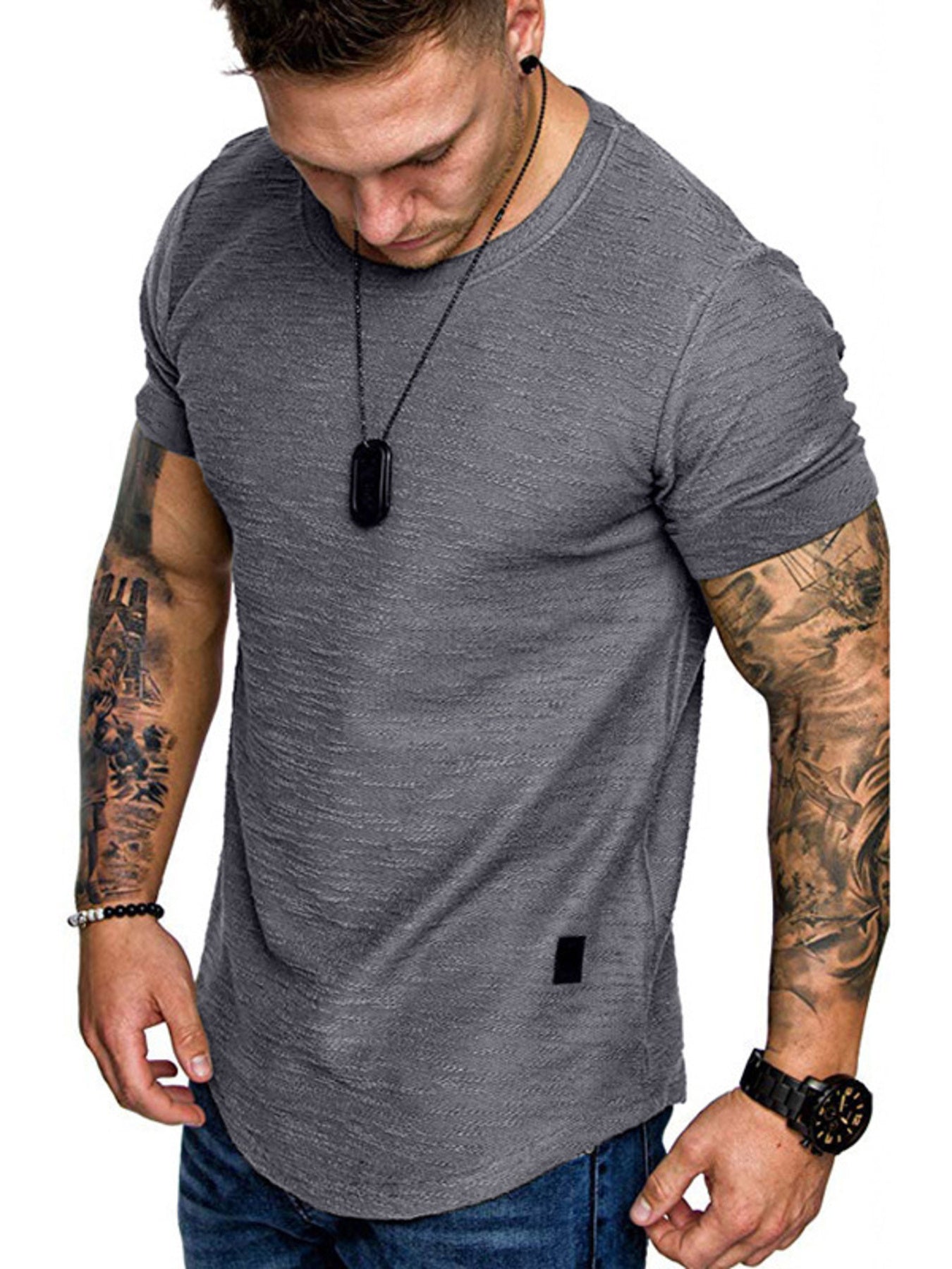 Man wearing a gray t-shirt with tattoos on arms on a white background