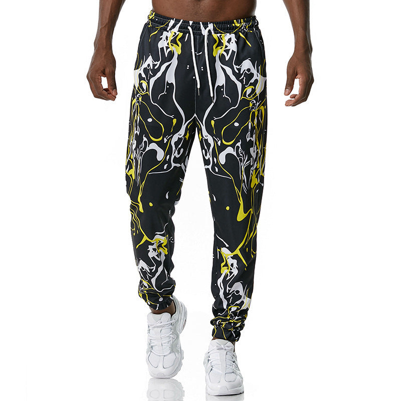 Black jogger pants with yellow and white abstract pattern worn by a person on a white background