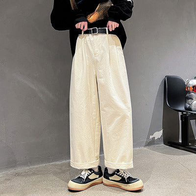 Person wearing beige wide-leg pants against a gray wall.