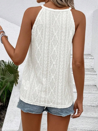 Person wearing a white lace top and denim shorts against a white wall.