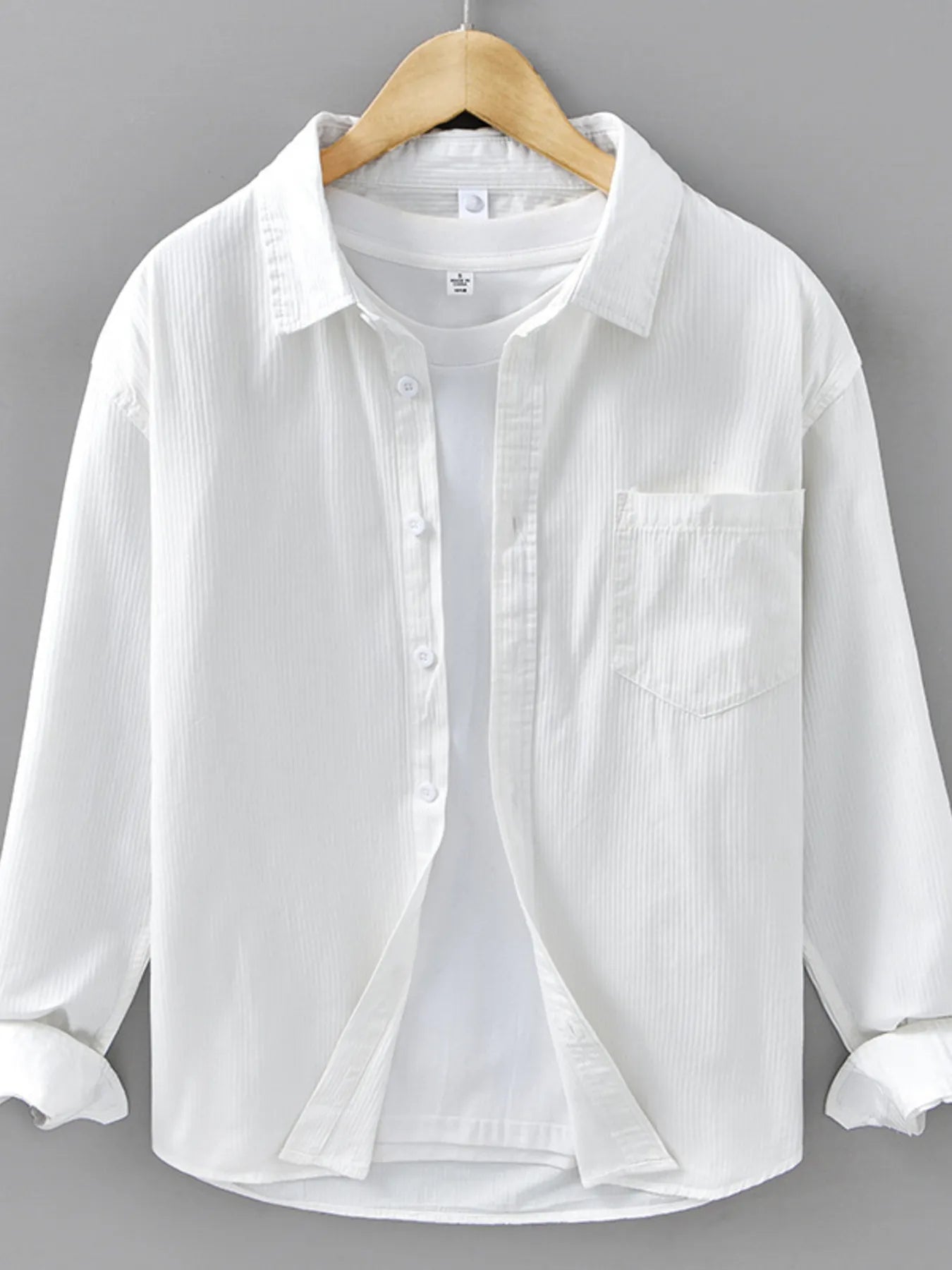 White button-up shirt on a wooden hanger against a gray background