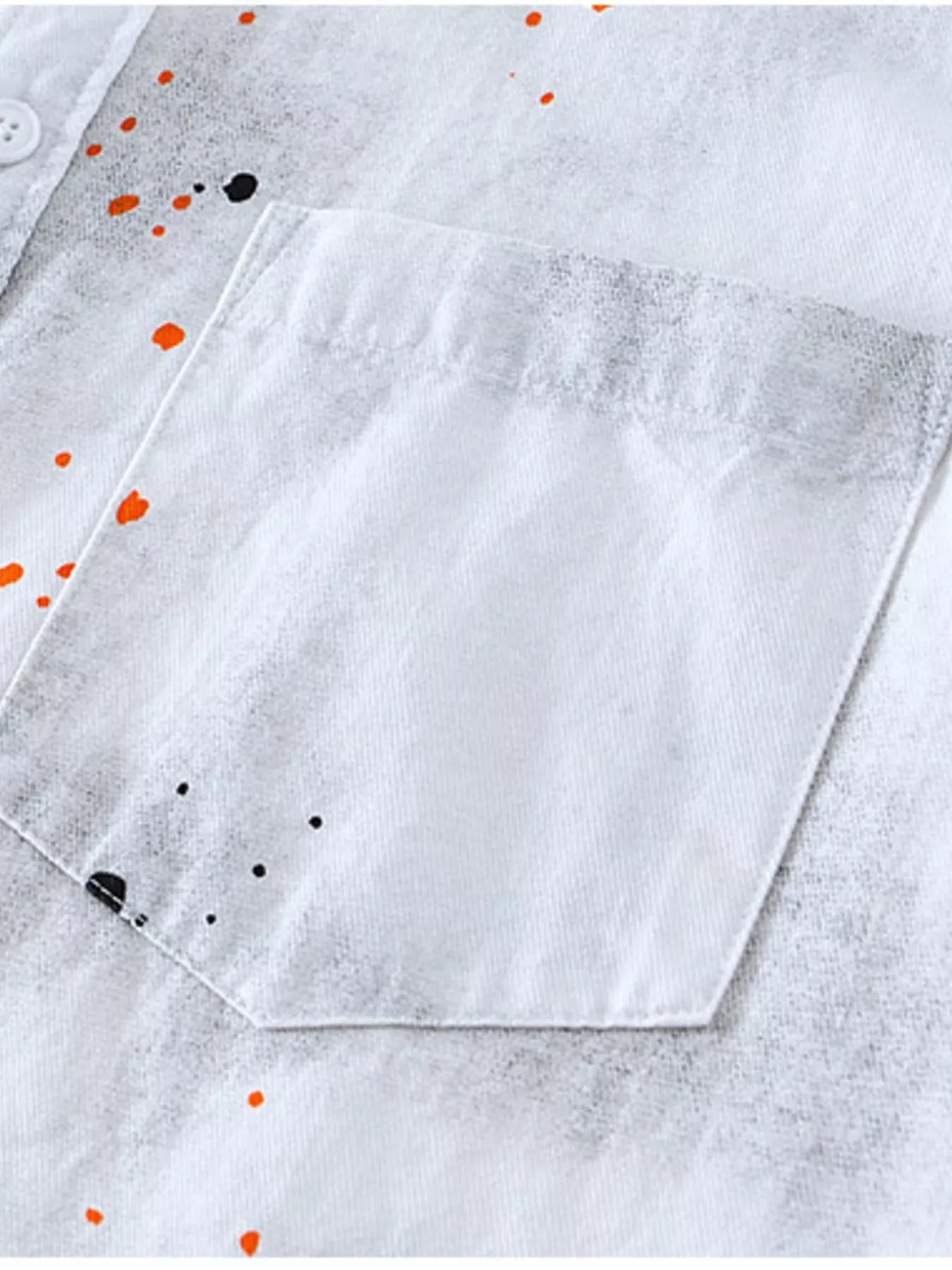 Close-up of a white shirt with orange and black dot pattern on a light gray background