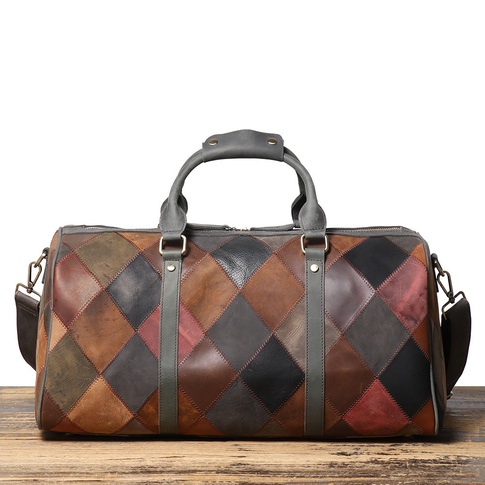 Patchwork leather duffel bag on a wooden surface with a white background