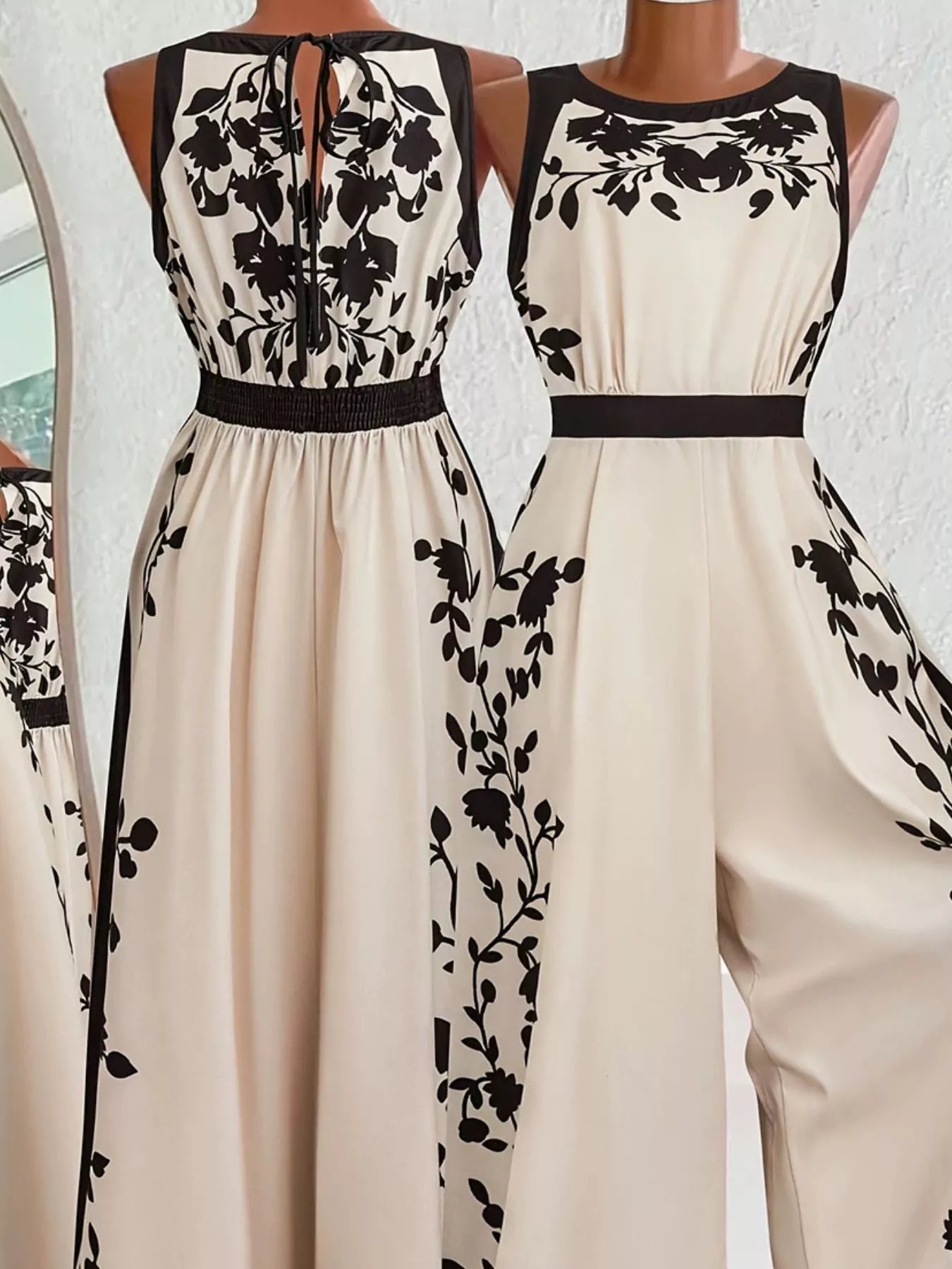 Beige sleeveless pants suit with black floral patterns on a white background