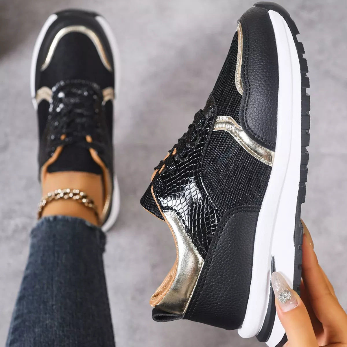 Black and gold sneakers with white soles on a gray background