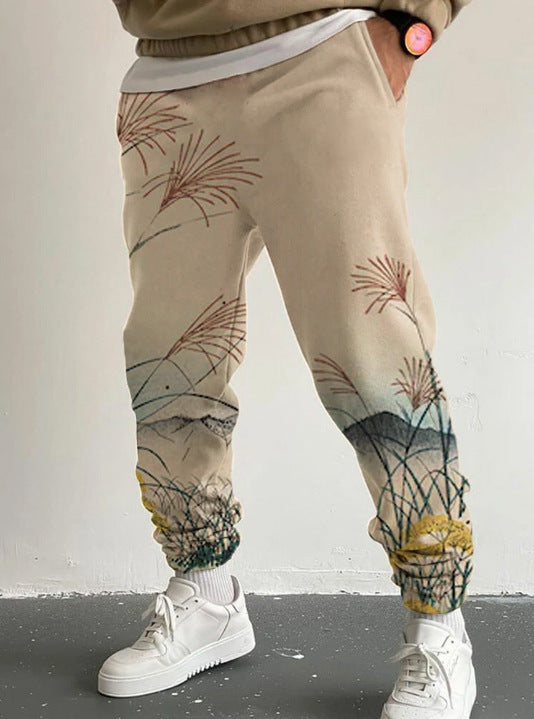 Beige jogger pants with nature-themed design worn by a person, standing against a plain background.