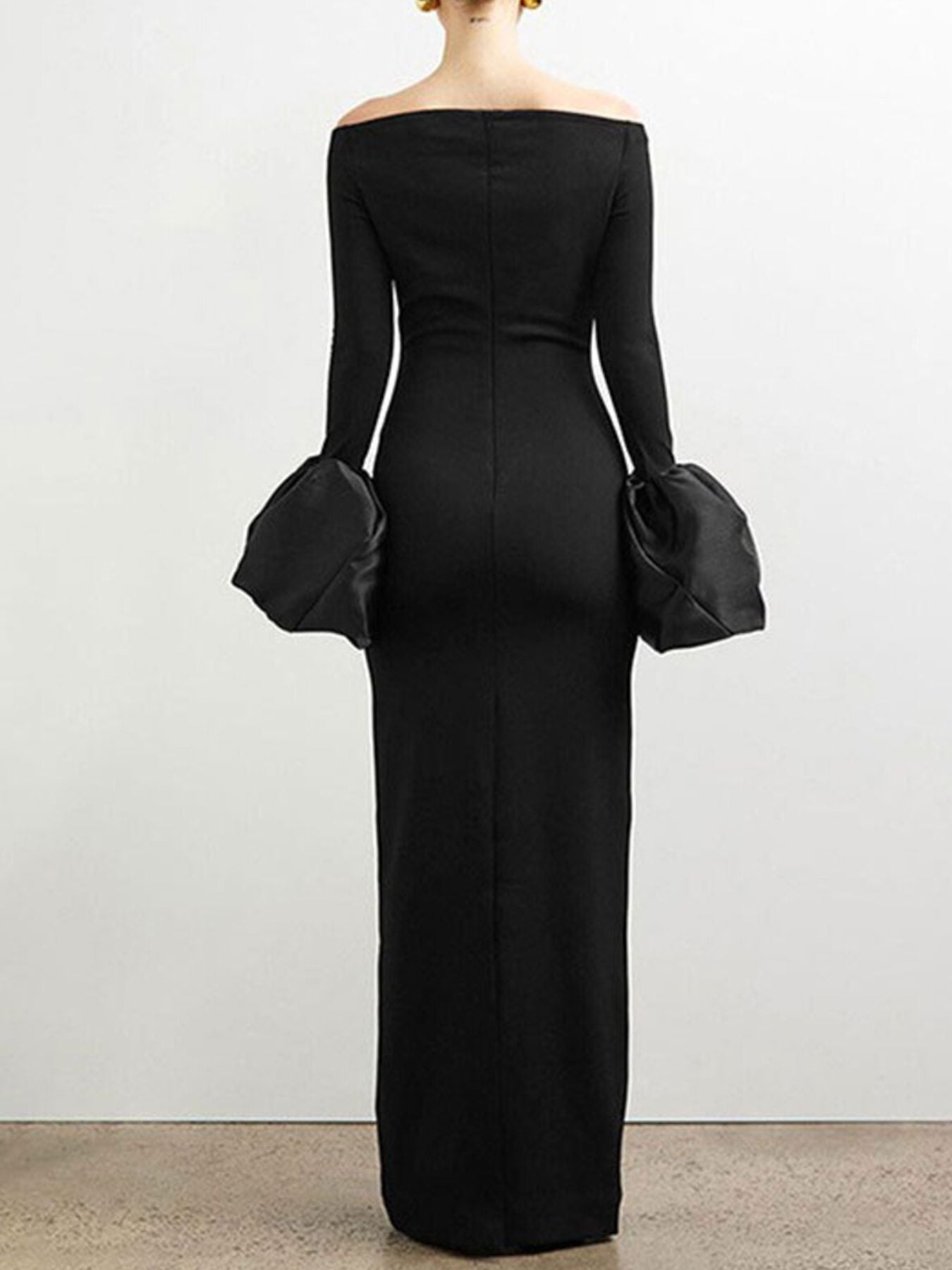 Black off-shoulder long-sleeve dress with matching black handbags on a plain background