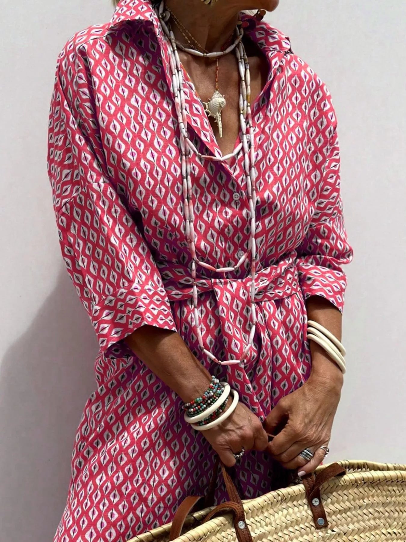 Person wearing a pink patterned dress with a plain background