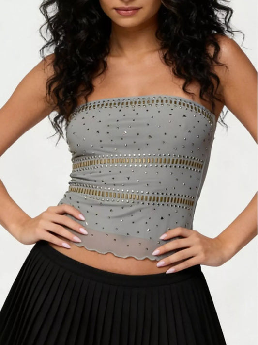 Woman wearing a gray strapless top with decorative elements on a plain background